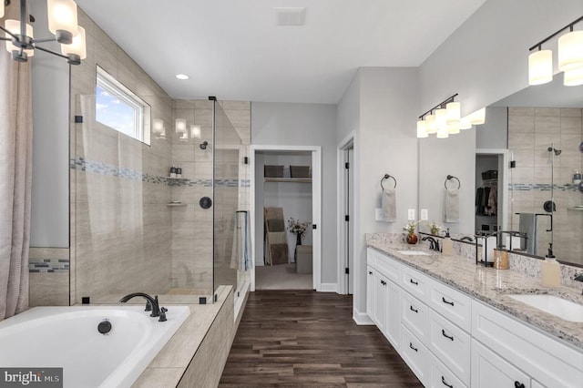 full bathroom featuring double vanity, a spacious closet, a stall shower, and a sink