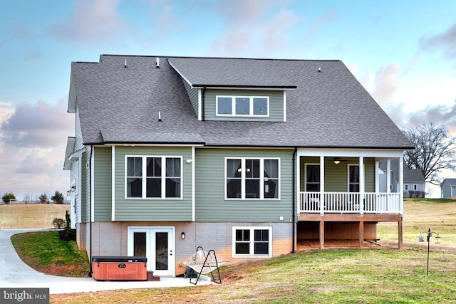 rear view of house featuring a patio, a hot tub, a yard, and a shingled roof