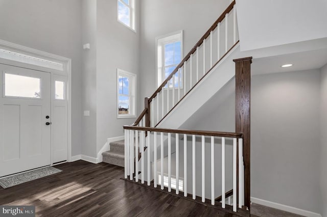 foyer with baseboards, a high ceiling, dark wood finished floors, and stairs