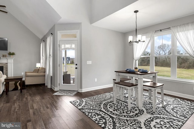 dining space featuring dark wood finished floors, plenty of natural light, baseboards, and vaulted ceiling