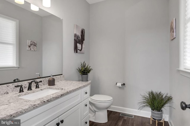 bathroom featuring vanity, wood finished floors, visible vents, baseboards, and toilet