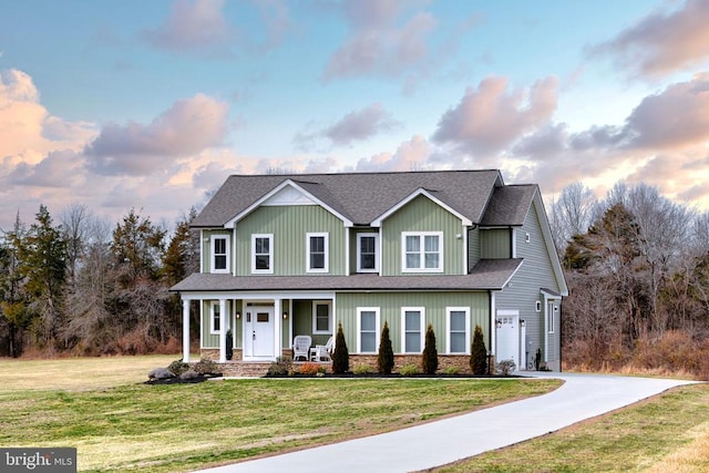 view of front facade with driveway, a porch, roof with shingles, a front yard, and a garage