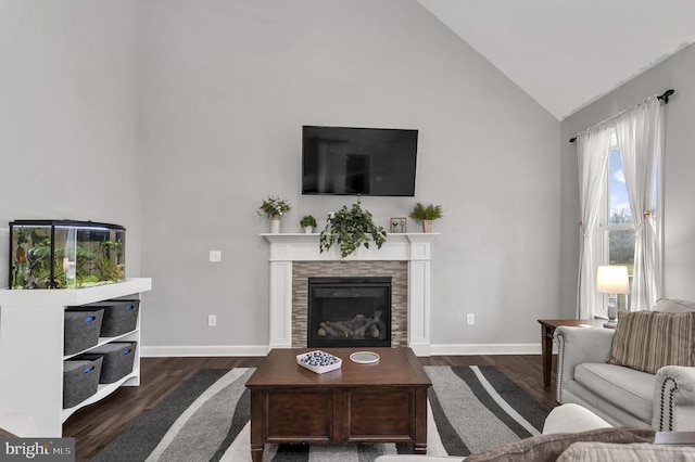 living area with baseboards, high vaulted ceiling, wood finished floors, and a fireplace