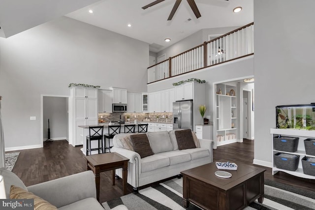 living area with dark wood-style floors, recessed lighting, a high ceiling, baseboards, and ceiling fan