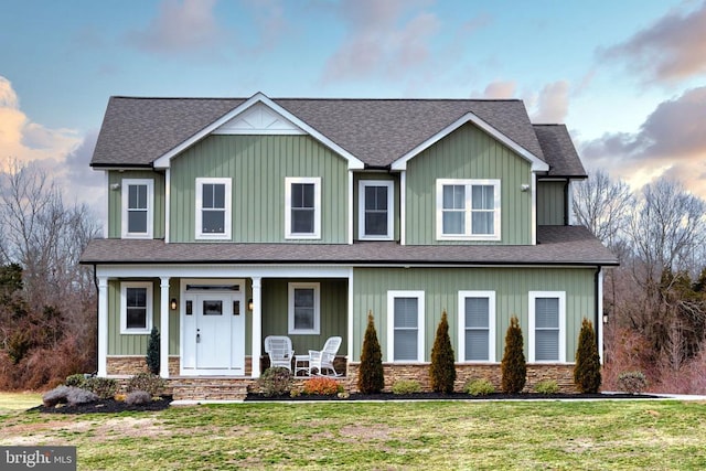 view of front of home featuring board and batten siding, a porch, stone siding, and a front yard