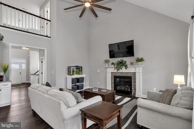 living room featuring dark wood-style floors, a high ceiling, a fireplace, baseboards, and ceiling fan