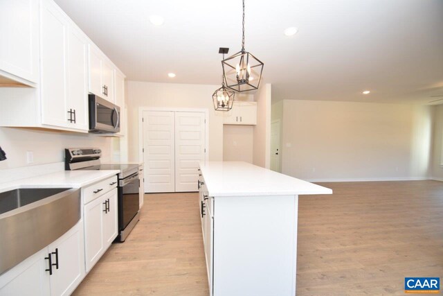 kitchen featuring stainless steel appliances, white cabinetry, hanging light fixtures, and a center island