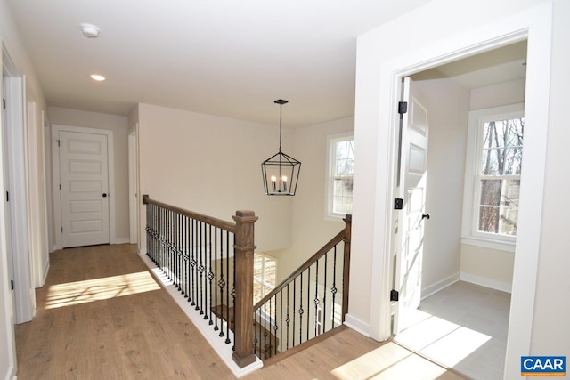 stairs featuring hardwood / wood-style floors, a wealth of natural light, and a chandelier