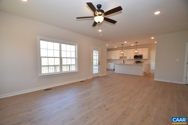 unfurnished living room with ceiling fan, sink, and light hardwood / wood-style flooring