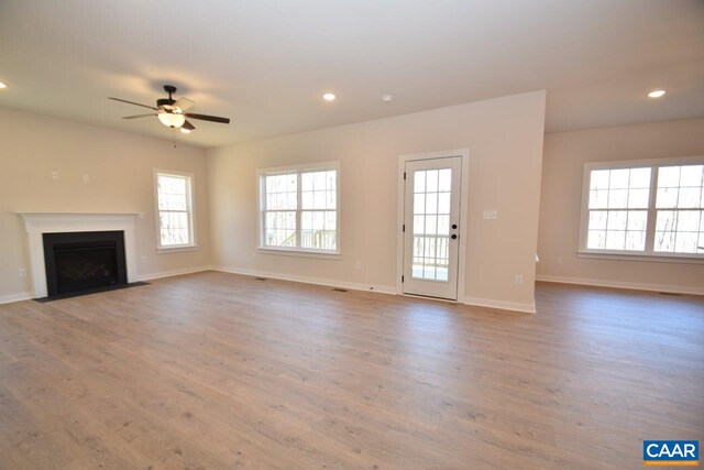 unfurnished living room featuring ceiling fan, light hardwood / wood-style flooring, and a healthy amount of sunlight