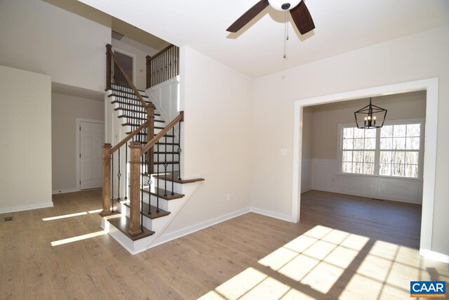 stairs featuring hardwood / wood-style floors and ceiling fan with notable chandelier