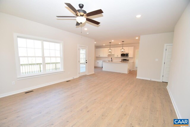 unfurnished living room with light hardwood / wood-style flooring and ceiling fan