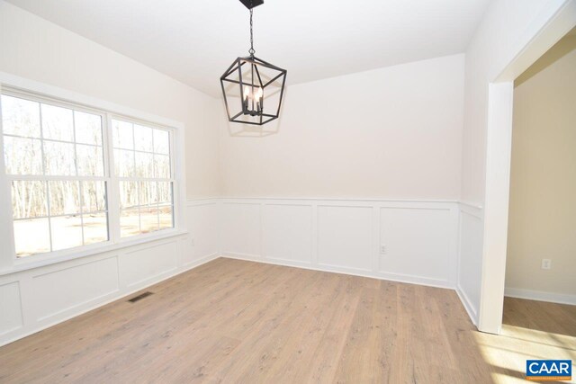 unfurnished dining area featuring a notable chandelier and light wood-type flooring