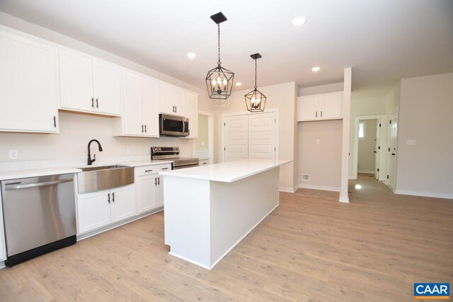 kitchen featuring white cabinetry, appliances with stainless steel finishes, decorative light fixtures, and a kitchen island