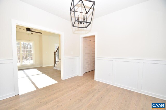 unfurnished dining area with ceiling fan with notable chandelier and light hardwood / wood-style floors