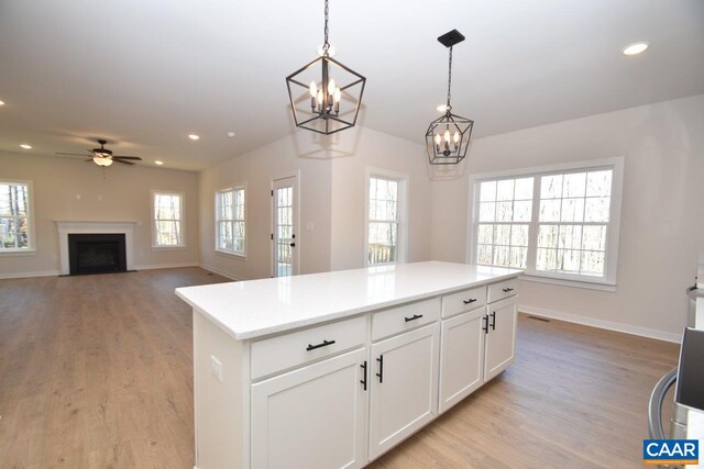 kitchen with hanging light fixtures, a center island, white cabinets, and light hardwood / wood-style flooring