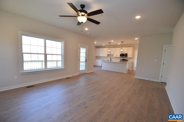 unfurnished living room with hardwood / wood-style flooring, sink, and ceiling fan