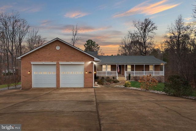 single story home with a porch, concrete driveway, brick siding, and an attached garage