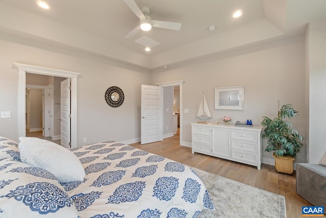 bedroom featuring ceiling fan, a raised ceiling, and light wood-type flooring