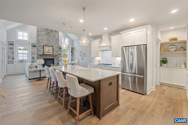 kitchen with premium range hood, decorative light fixtures, white cabinetry, a kitchen island with sink, and stainless steel appliances