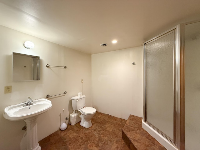 bathroom with a shower with door and toilet