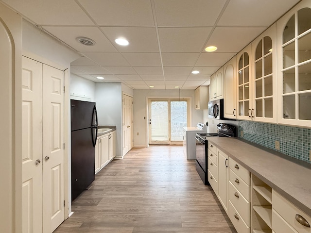 kitchen with backsplash, a paneled ceiling, light hardwood / wood-style floors, and black appliances