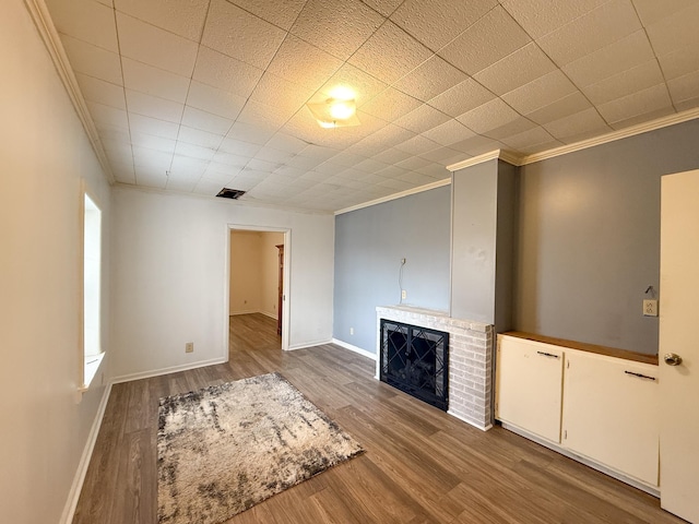 unfurnished living room featuring wood-type flooring, a brick fireplace, and ornamental molding