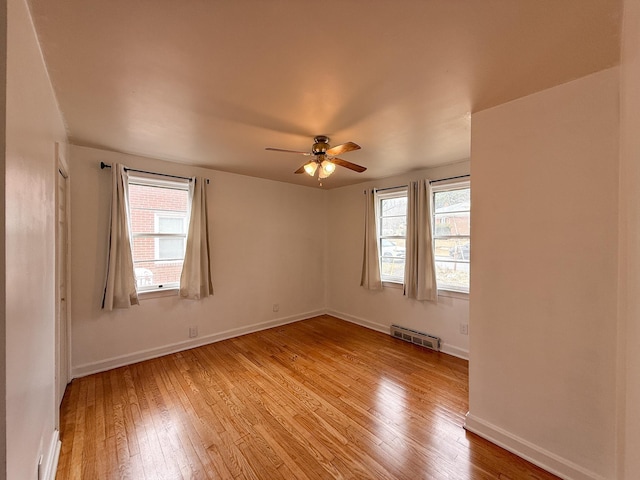 spare room with ceiling fan, a wealth of natural light, and light wood-type flooring