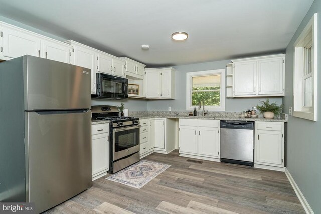 kitchen featuring sink, light wood-type flooring, white cabinets, and appliances with stainless steel finishes