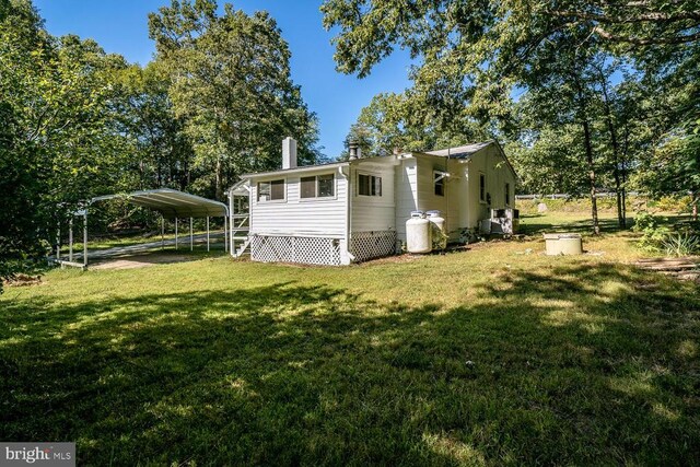 back of property with a carport and a yard