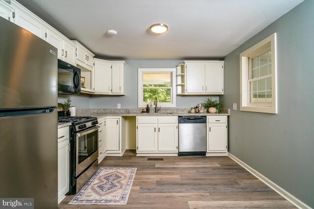 kitchen featuring sink, stainless steel appliances, dark hardwood / wood-style floors, light stone countertops, and white cabinets