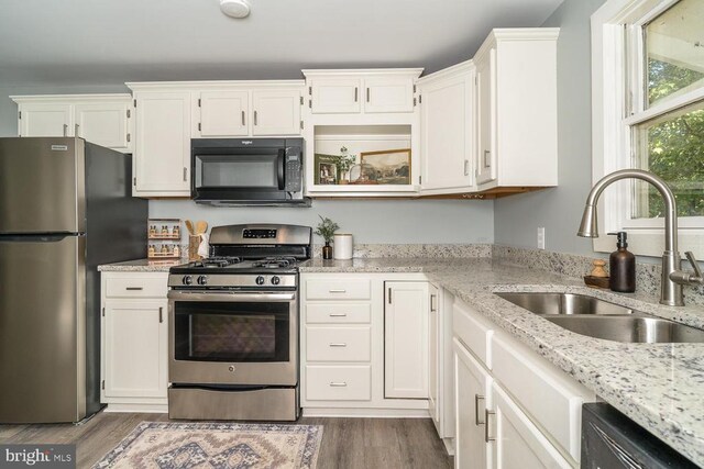 kitchen with white cabinetry, sink, and black appliances