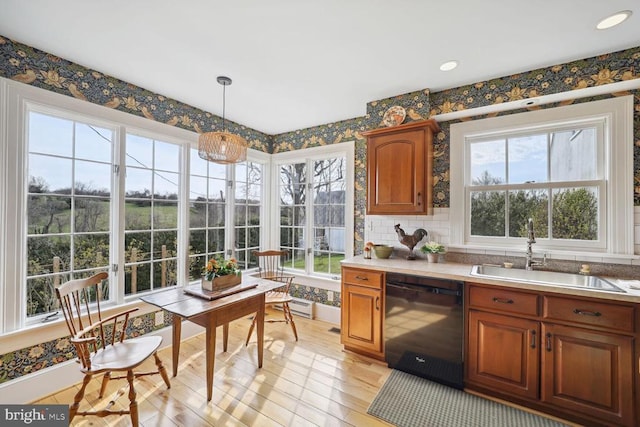 kitchen featuring brown cabinets, light wood finished floors, a sink, dishwasher, and wallpapered walls