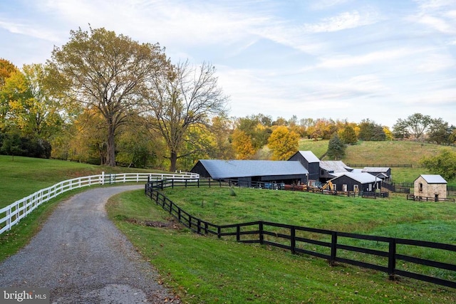 exterior space with a yard, fence, an outbuilding, and a rural view