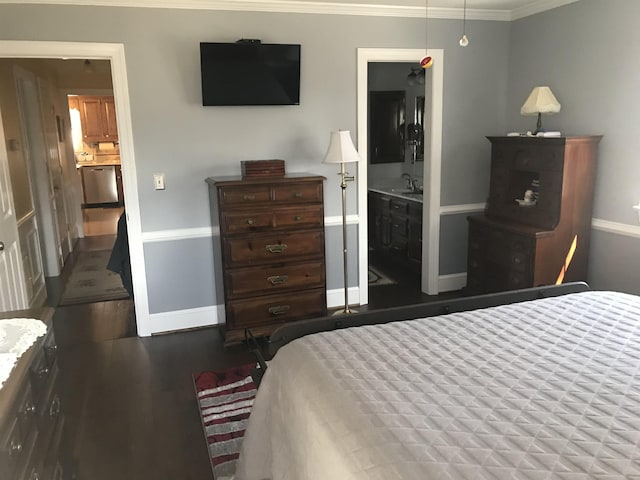 bedroom with a sink, crown molding, baseboards, and wood finished floors