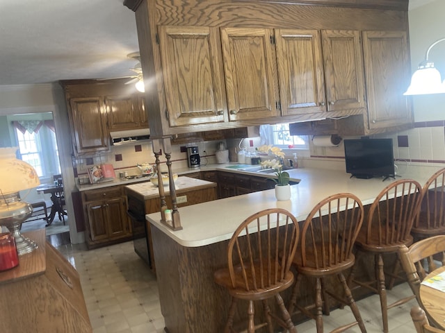 kitchen featuring a breakfast bar, light countertops, a peninsula, and light floors