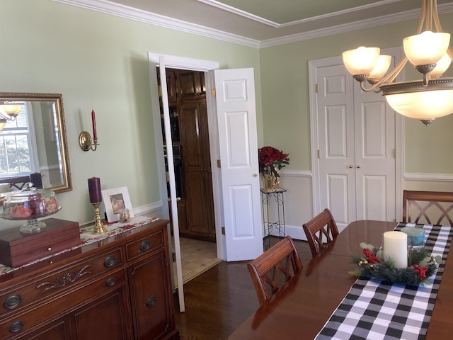 dining area featuring ornamental molding, dark wood-style flooring, and an inviting chandelier