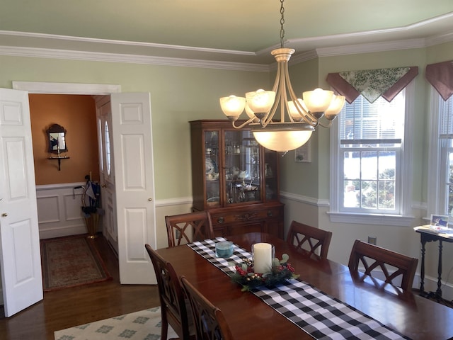 dining area featuring dark wood-style floors, crown molding, a wainscoted wall, and an inviting chandelier