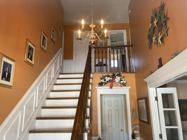 staircase featuring a towering ceiling and an inviting chandelier