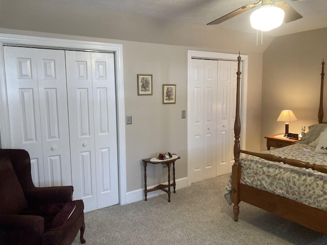 bedroom with a ceiling fan, baseboards, multiple closets, and light colored carpet