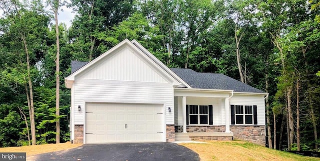 view of front of home with a garage, stone siding, and driveway