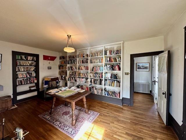 office with radiator, built in shelves, and wood-type flooring