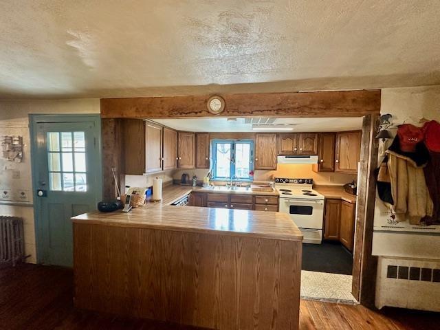 kitchen with radiator heating unit, white electric range oven, light hardwood / wood-style floors, a textured ceiling, and kitchen peninsula