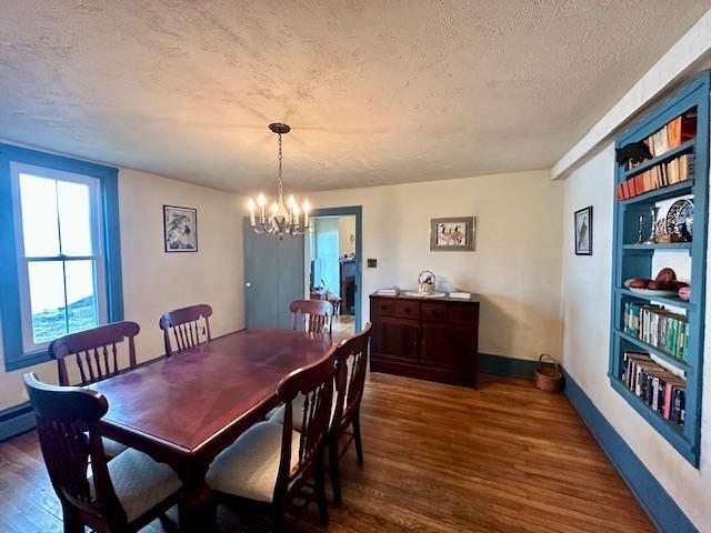 dining space featuring built in shelves, dark hardwood / wood-style flooring, a textured ceiling, and a notable chandelier