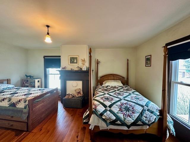 bedroom with a large fireplace and wood-type flooring