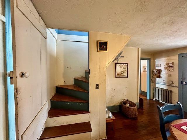 stairway featuring radiator, hardwood / wood-style floors, and a textured ceiling