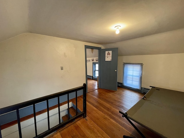 interior space featuring lofted ceiling, a baseboard heating unit, and hardwood / wood-style flooring