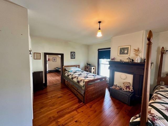 bedroom with radiator heating unit and dark hardwood / wood-style floors