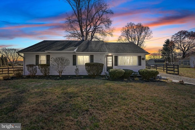 view of front of house featuring a yard, roof with shingles, and fence