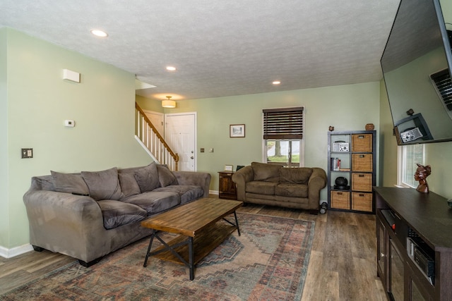 living room featuring dark wood-type flooring and a textured ceiling